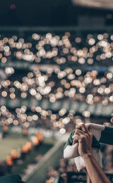 Fan holding green and white scarf at football game